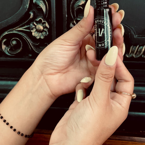 Female hands holding a roller perfume bottle, and applying the fragrance oil on the wrist. 