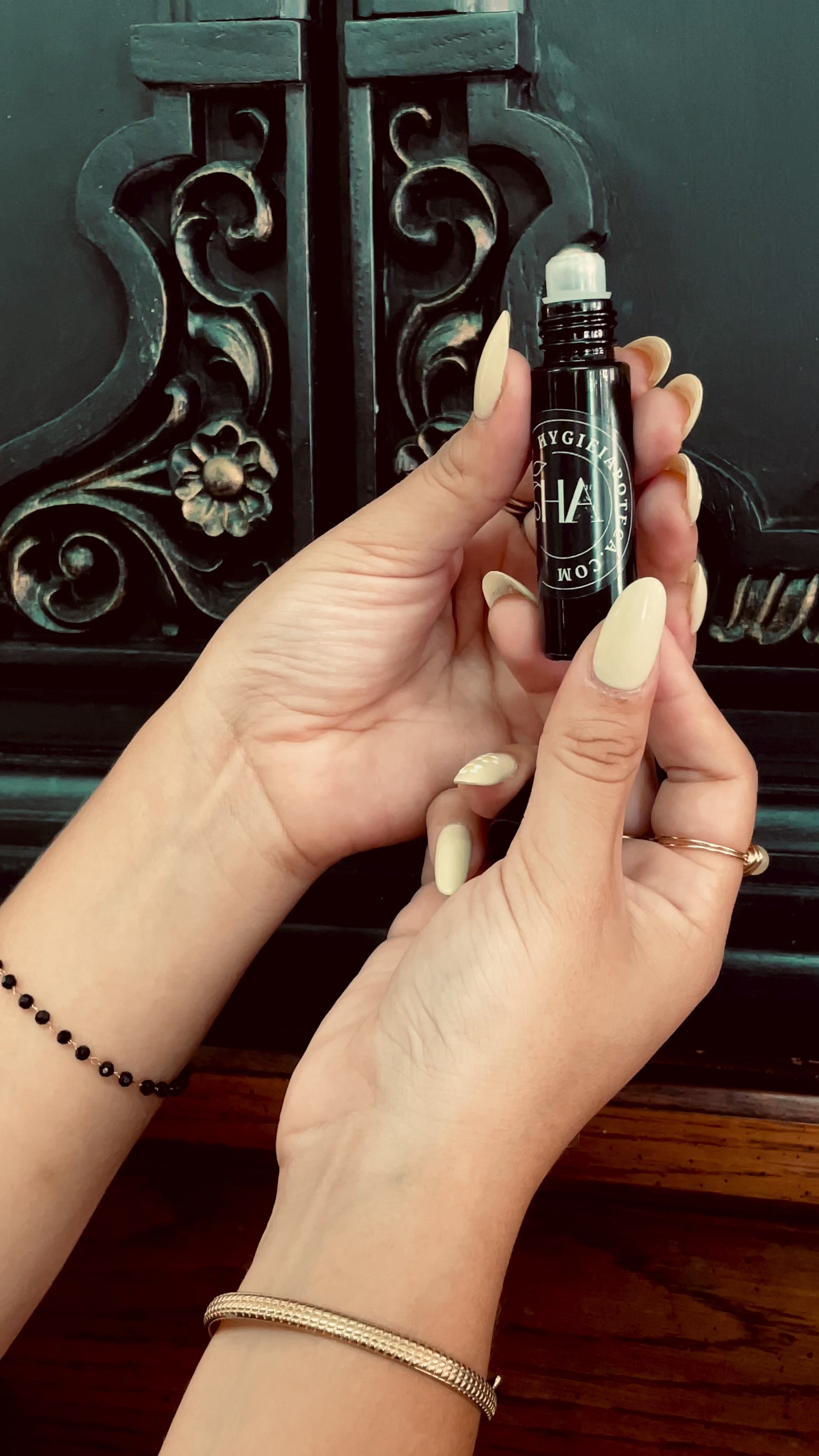 Female hands holding a roller perfume bottle, and applying the fragrance oil on the wrist. 